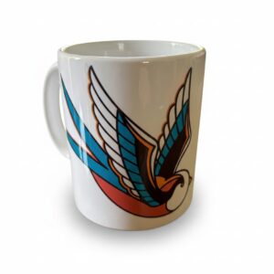 Une tasse blanche avec une hirondelle en motif tatouage traditionnel américain avec des larmes noires qui tombent.
