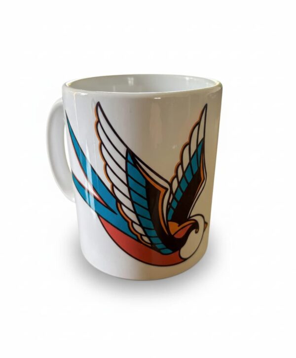 Une tasse blanche avec une hirondelle en motif tatouage traditionnel américain avec des larmes noires qui tombent.